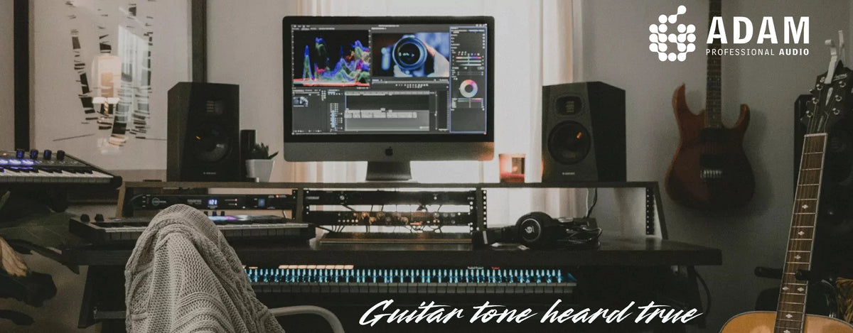 ADAM Audio studio monitors on a home-studio desk with guitars on the wall, "Guitar tone heard true"